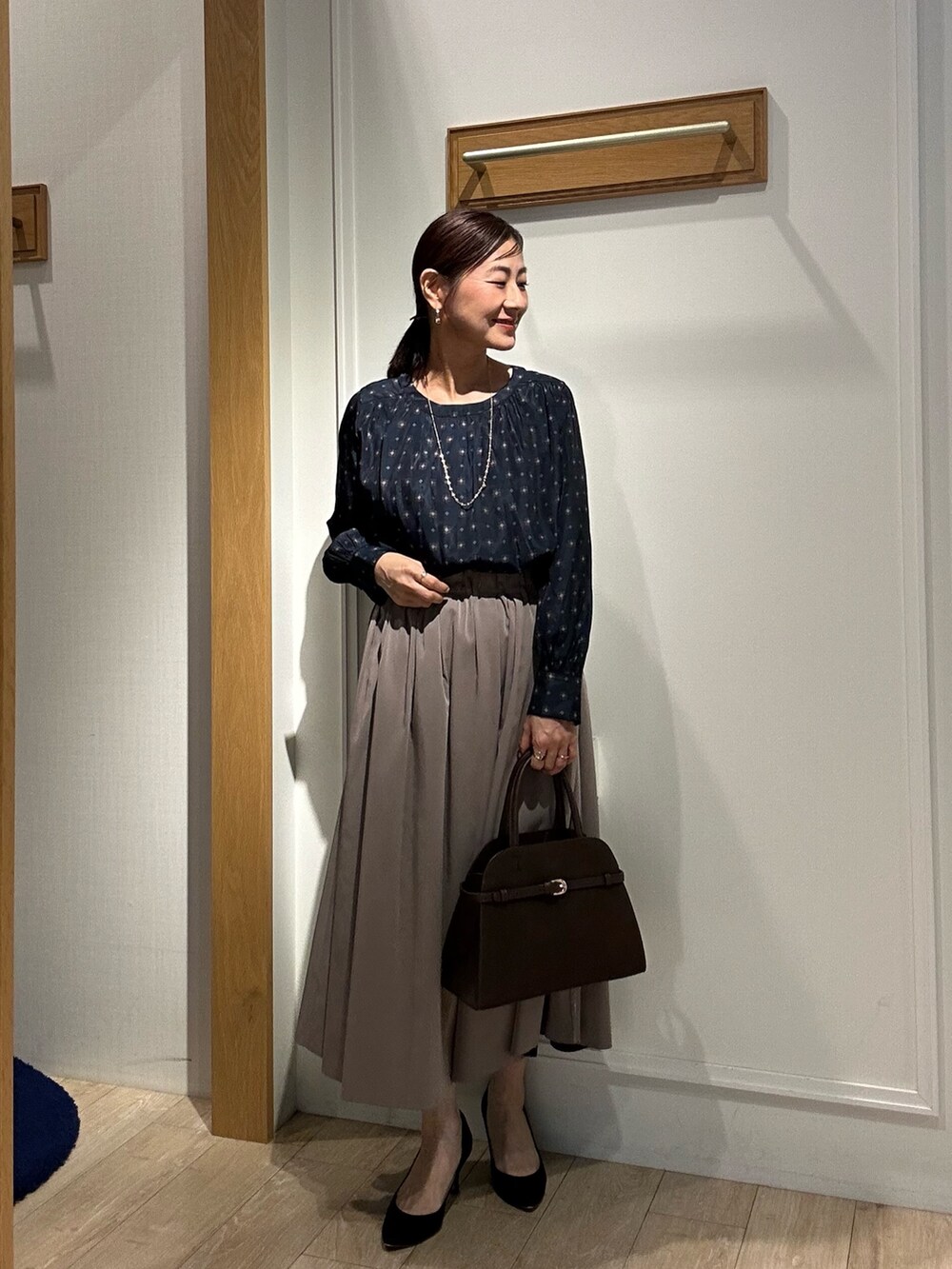 グレー系のテーラードジャケット、ブラウン系のスカート、ブルー系のシャツ/ブラウスを着用したレディースの秋コーディネートの9枚目の写真