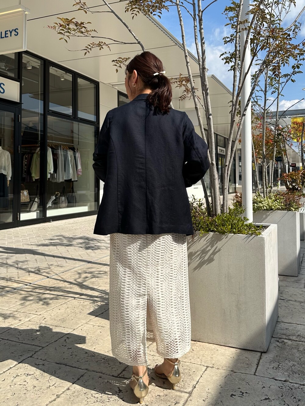 ブルー系のテーラードジャケット、ホワイト系のスカート、イエロー系のショルダーバッグを着用したレディースの春コーディネートの3枚目の写真