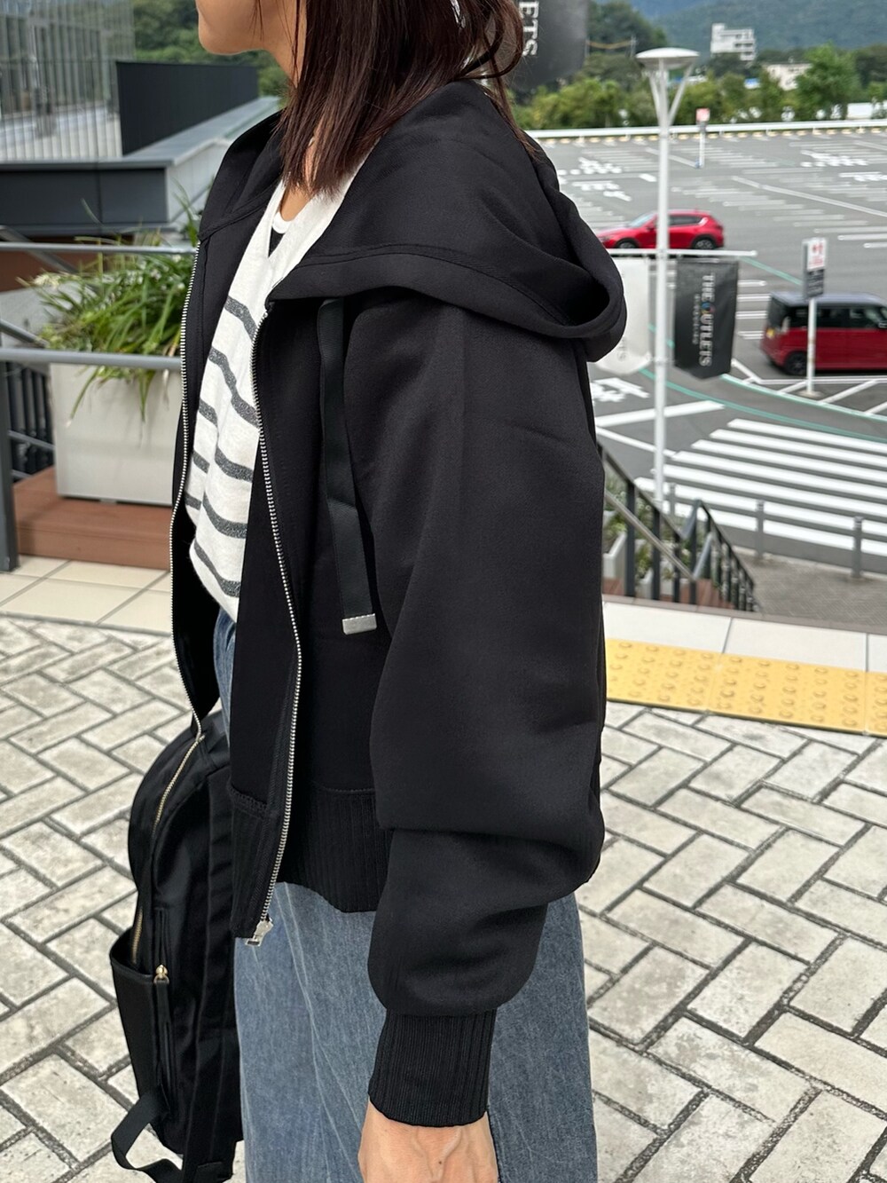 ブラック系のパーカー、ブルー系のデニムパンツ、ブラック系のバックパック/リュックを着用したレディースの秋コーディネートの7枚目の写真