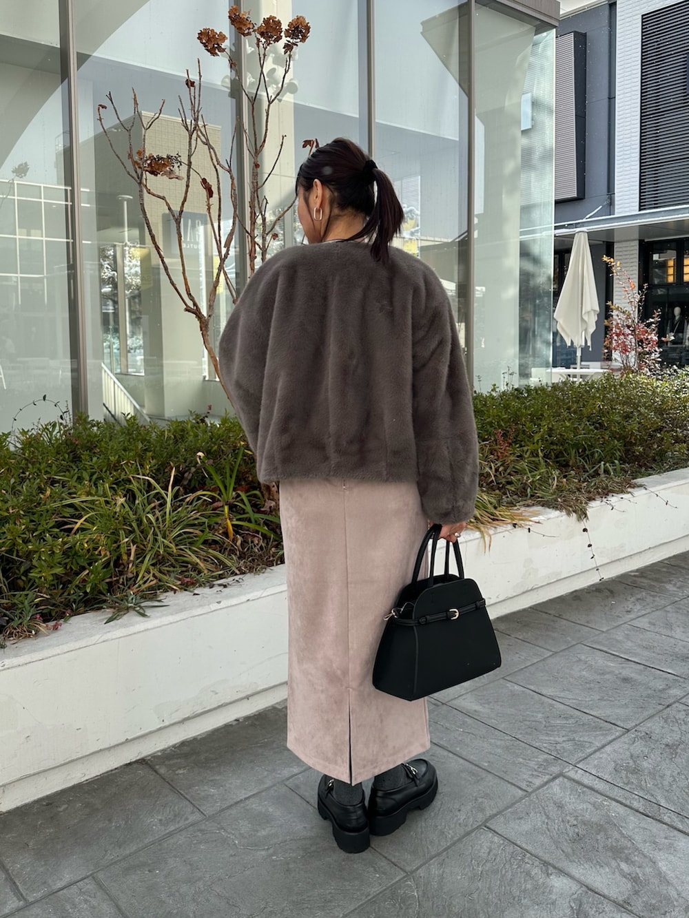 グレー系のブルゾン、グレー系のニット/セーター、ピンク系のスカートを着用したレディースの冬コーディネートの3枚目の写真