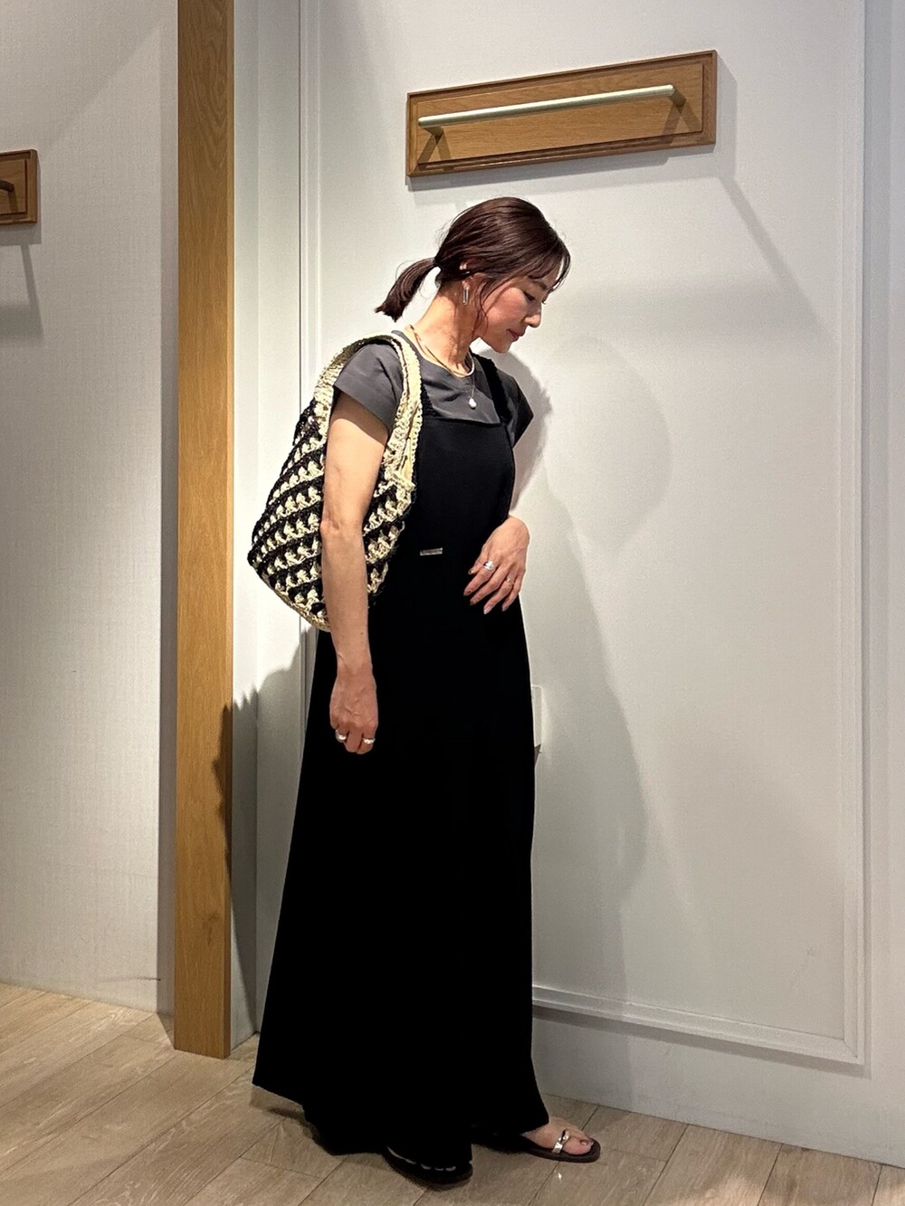 ブラック系のワンピース、ホワイト系のカーディガン/ボレロ、ゴールド系のネックレスを着用したレディースの夏コーディネートの8枚目の写真