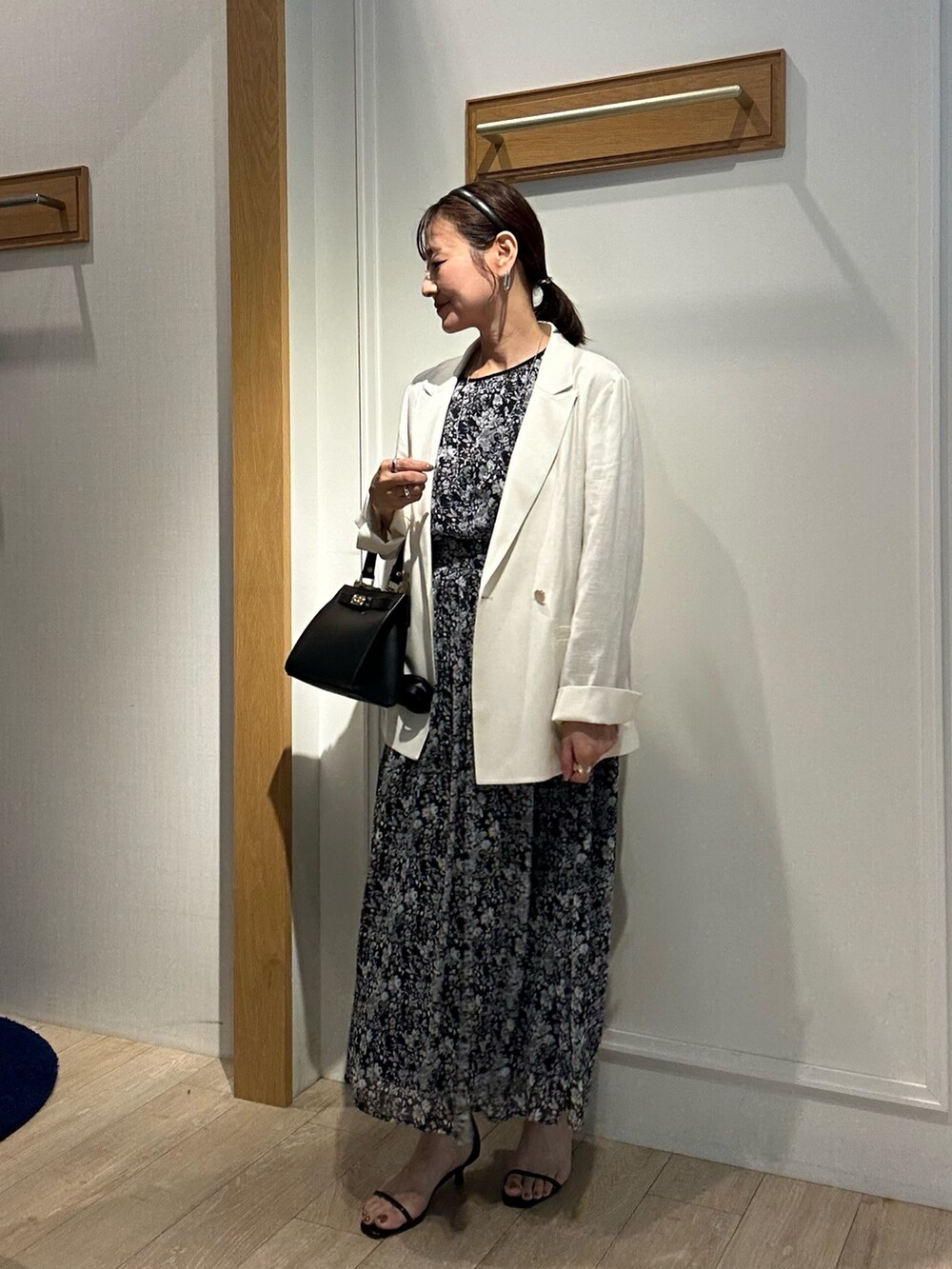 ブラック系のワンピース、ホワイト系のテーラードジャケット、ブラック系のショルダーバッグを着用したレディースの夏コーディネートの2枚目の写真