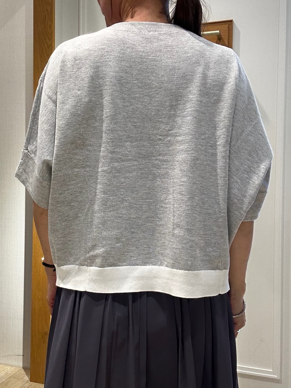 ブラック系のショルダーバッグ、グレー系のニット/セーター、ホワイト系のスカートを着用したレディースの秋コーディネートの6枚目の写真
