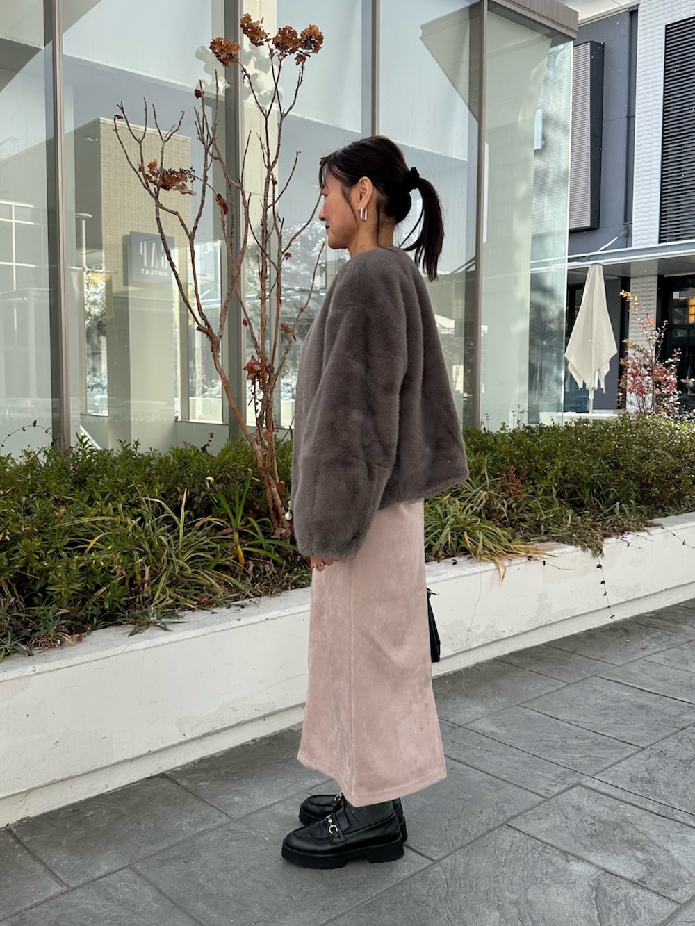 グレー系のブルゾン、グレー系のニット/セーター、ピンク系のスカートを着用したレディースの冬コーディネートの2枚目の写真