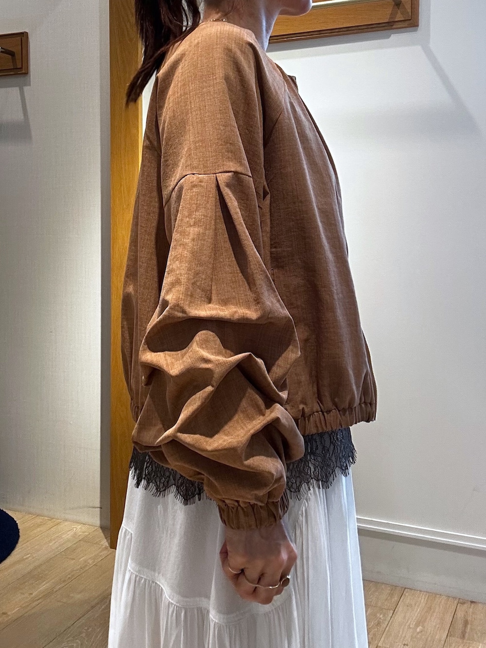 イエロー系のブルゾン、ブラウン系のTシャツ/カットソー、ホワイト系のスカートを着用したレディースの春コーディネートの5枚目の写真