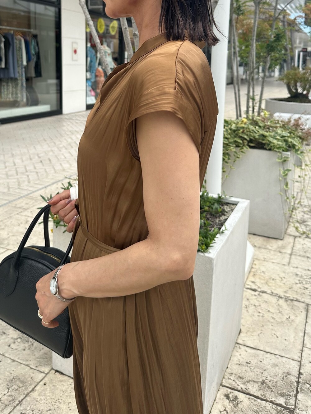 ブラウン系のワンピース、ブラック系のボストンバッグ、ブラック系のサンダルを着用したレディースの夏コーディネートの5枚目の写真