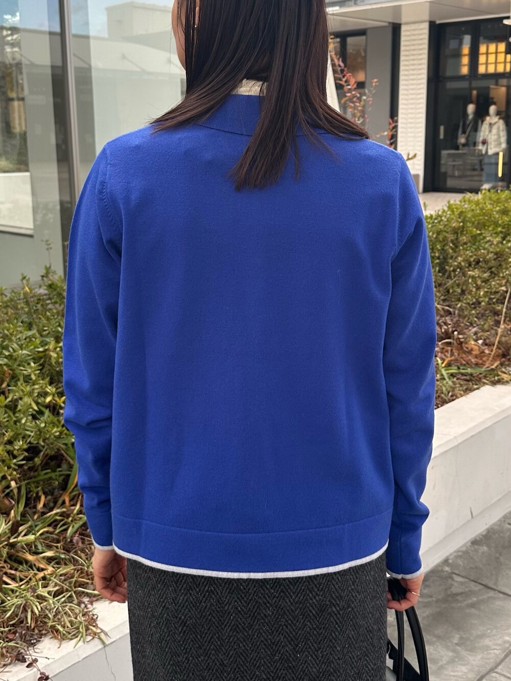 ブルー系のカーディガン/ボレロ、グレー系のスカート、ブラック系のトートバッグを着用したレディースの冬コーディネートの6枚目の写真