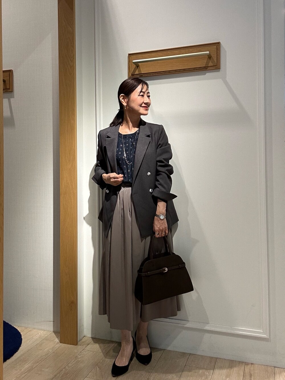 グレー系のテーラードジャケット、ブラウン系のスカート、ブルー系のシャツ/ブラウスを着用したレディースの秋コーディネートの5枚目の写真