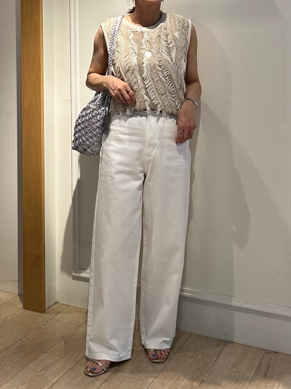 ベージュ系のニット/セーター、ホワイト系のデニムパンツ、ゴールド系のヘアゴムを着用したレディースの夏コーディネートの5枚目の写真