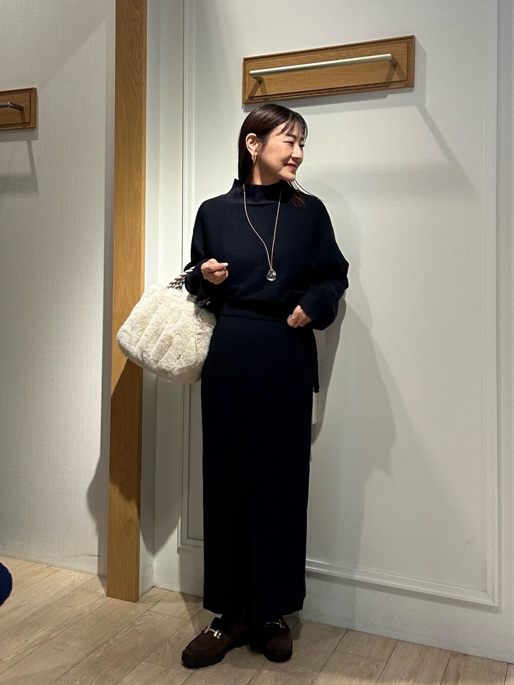 ホワイト系のトートバッグ、ブラウン系のローファー、ブルー系のニット/セーターを着用したレディースの冬コーディネートの5枚目の写真