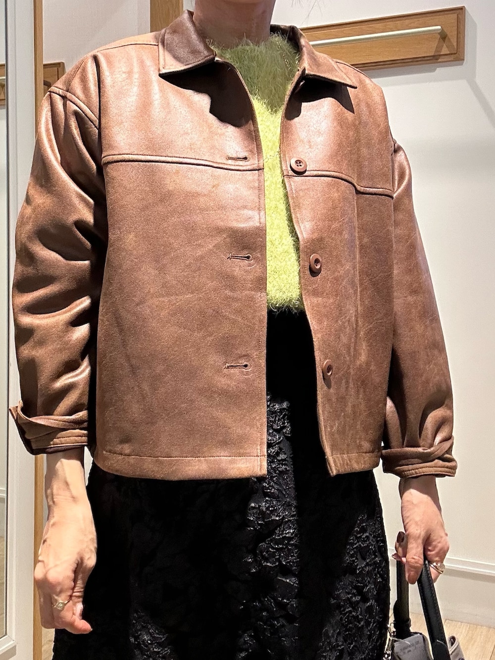 イエロー系のブルゾン、グリーン系のニット/セーター、グレー系のスカートを着用したレディースの秋コーディネートの5枚目の写真