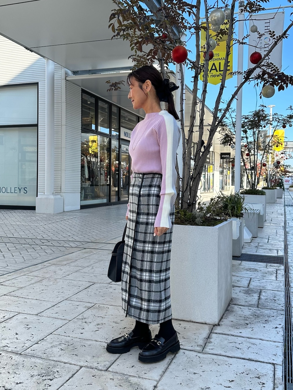 グレー系のスカート、ブラック系のトートバッグ、ピンク系のニット/セーターを着用したレディースの秋コーディネートの3枚目の写真