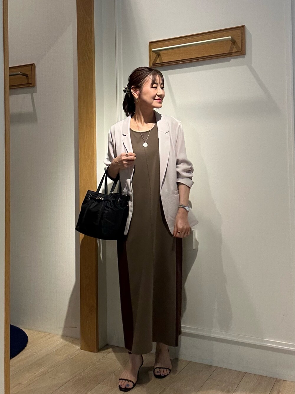 ブラウン系のワンピース、ブラック系のサンダル、ベージュ系のテーラードジャケットを着用したレディースの夏コーディネートの9枚目の写真