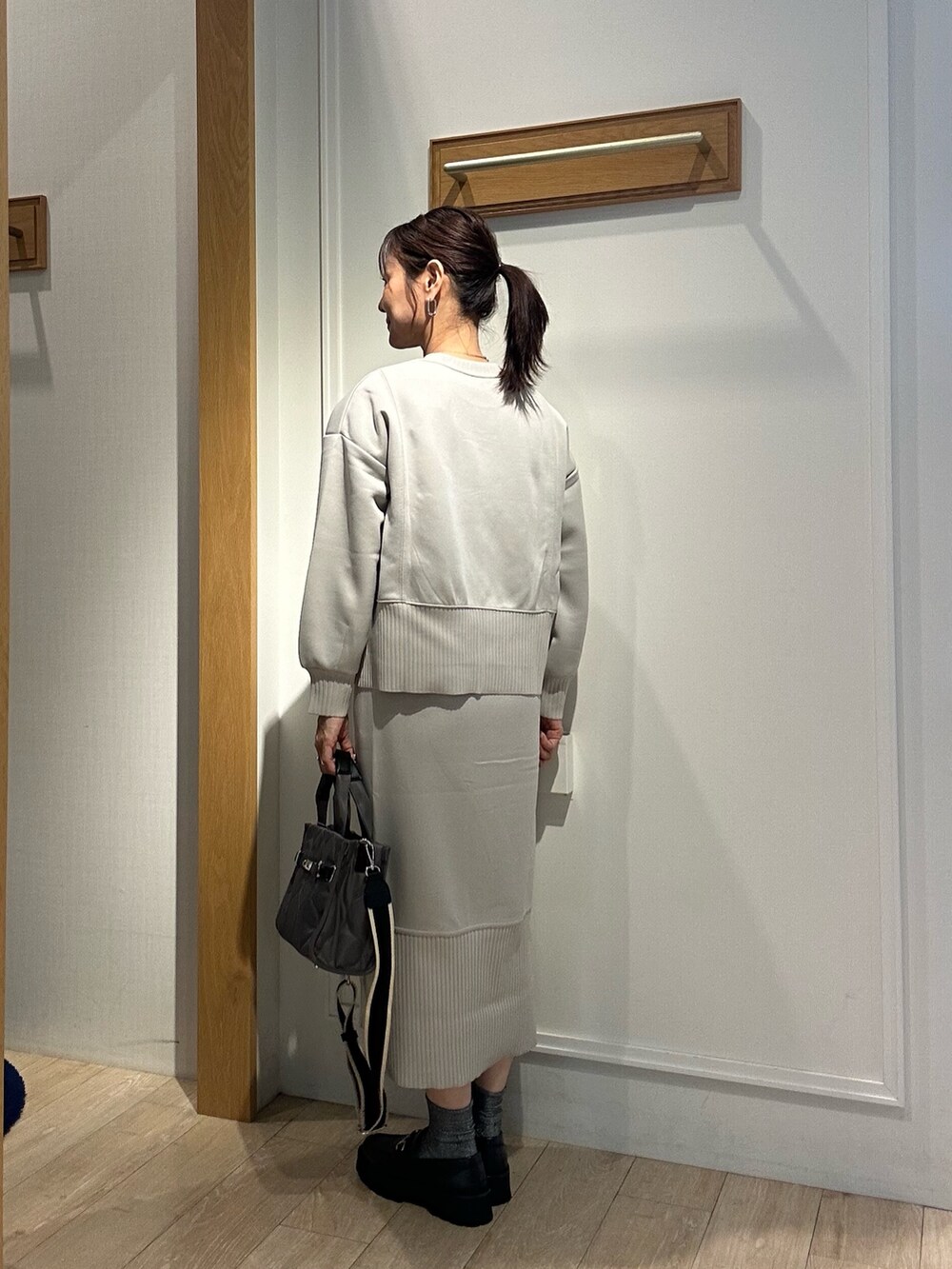 グレー系のトートバッグ、ベージュ系のスカート、ベージュ系のTシャツ/カットソーを着用したレディースの秋コーディネートの5枚目の写真