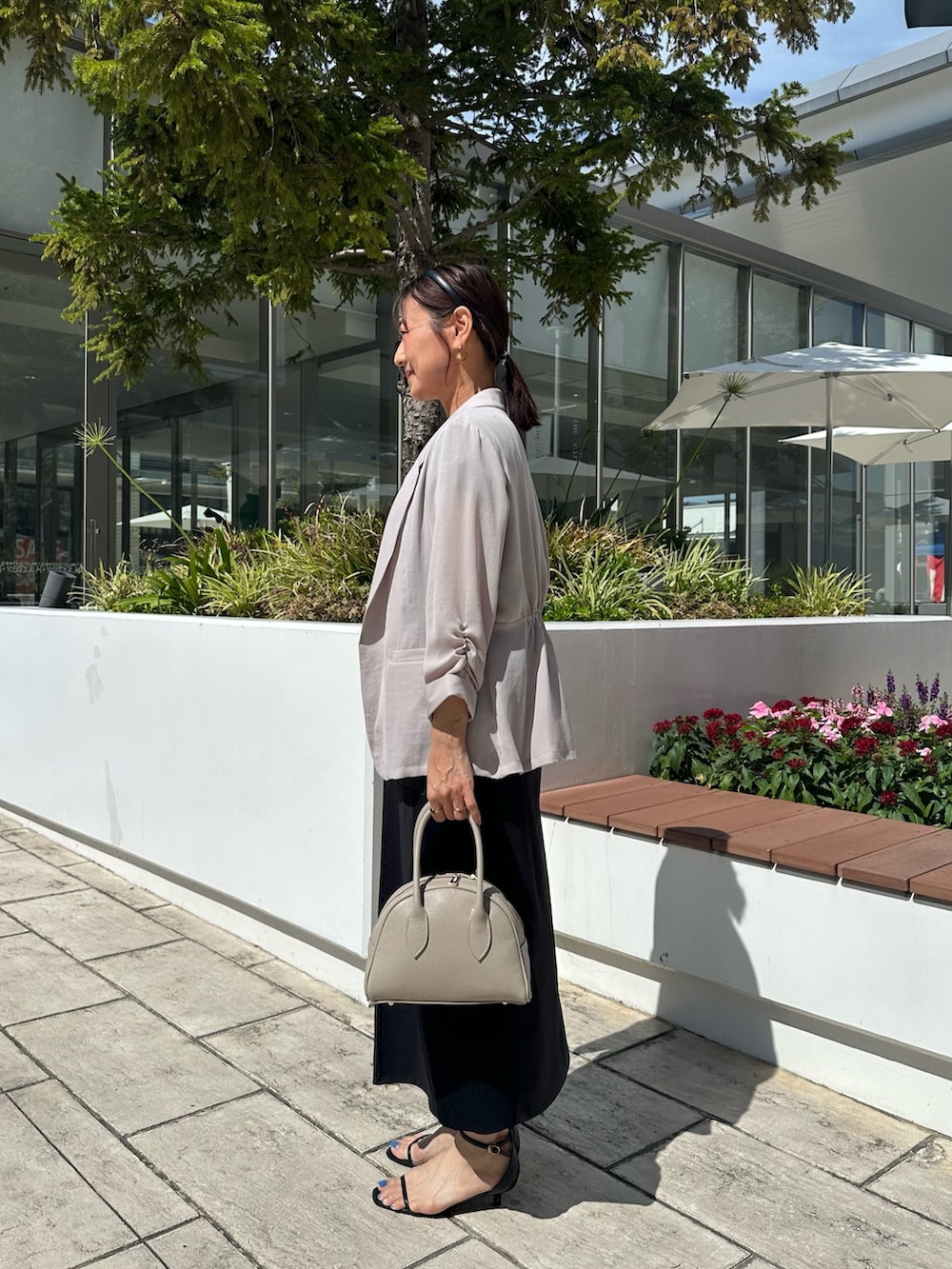 ベージュ系のテーラードジャケット、ブラック系のシャツ/ブラウス、ベージュ系のボストンバッグを着用したレディースの夏コーディネートの2枚目の写真