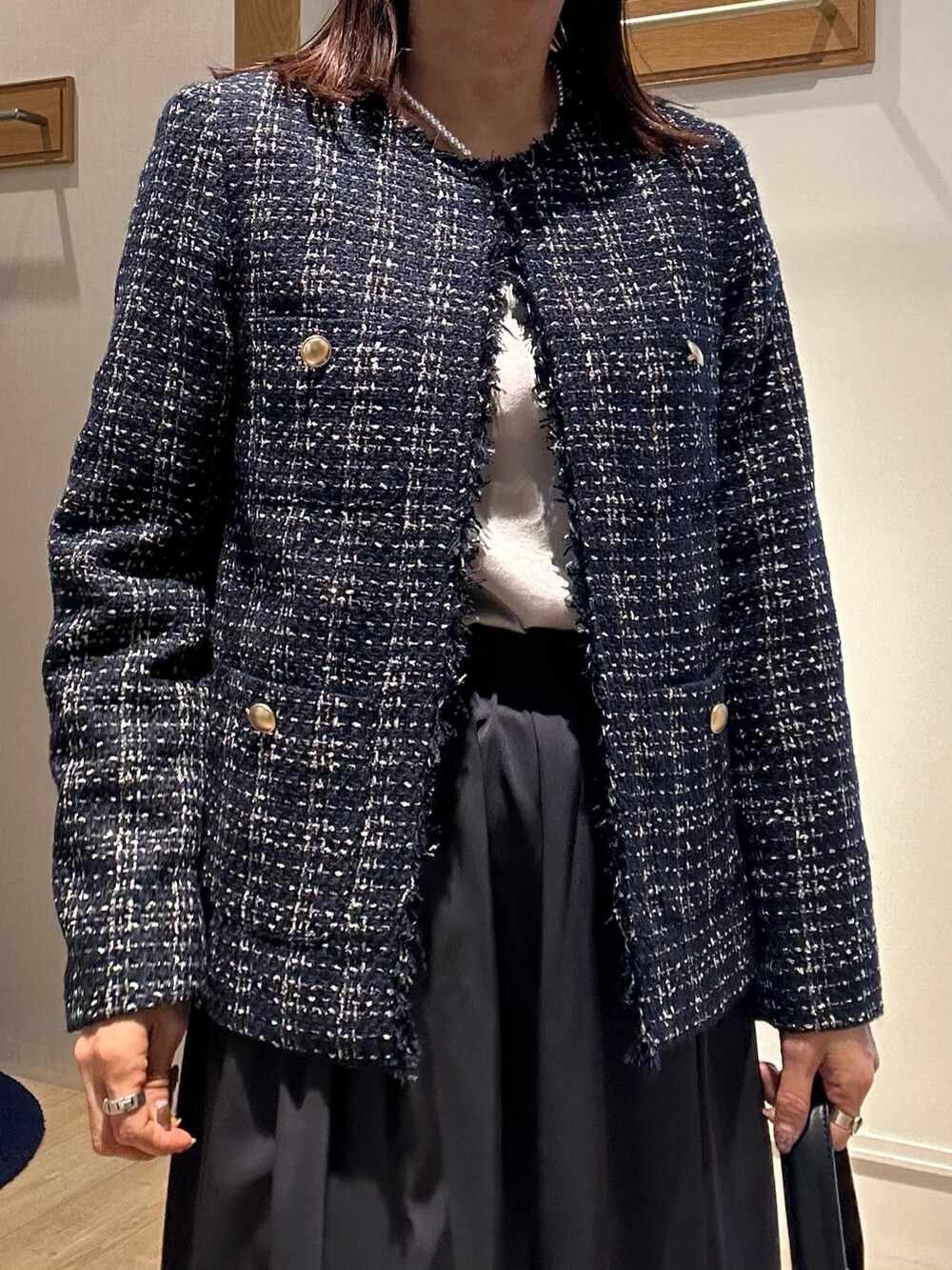 ブルー系のノーカラージャケット、ホワイト系のTシャツ/カットソー、ベージュ系のスカートを着用したレディースの冬コーディネートの5枚目の写真