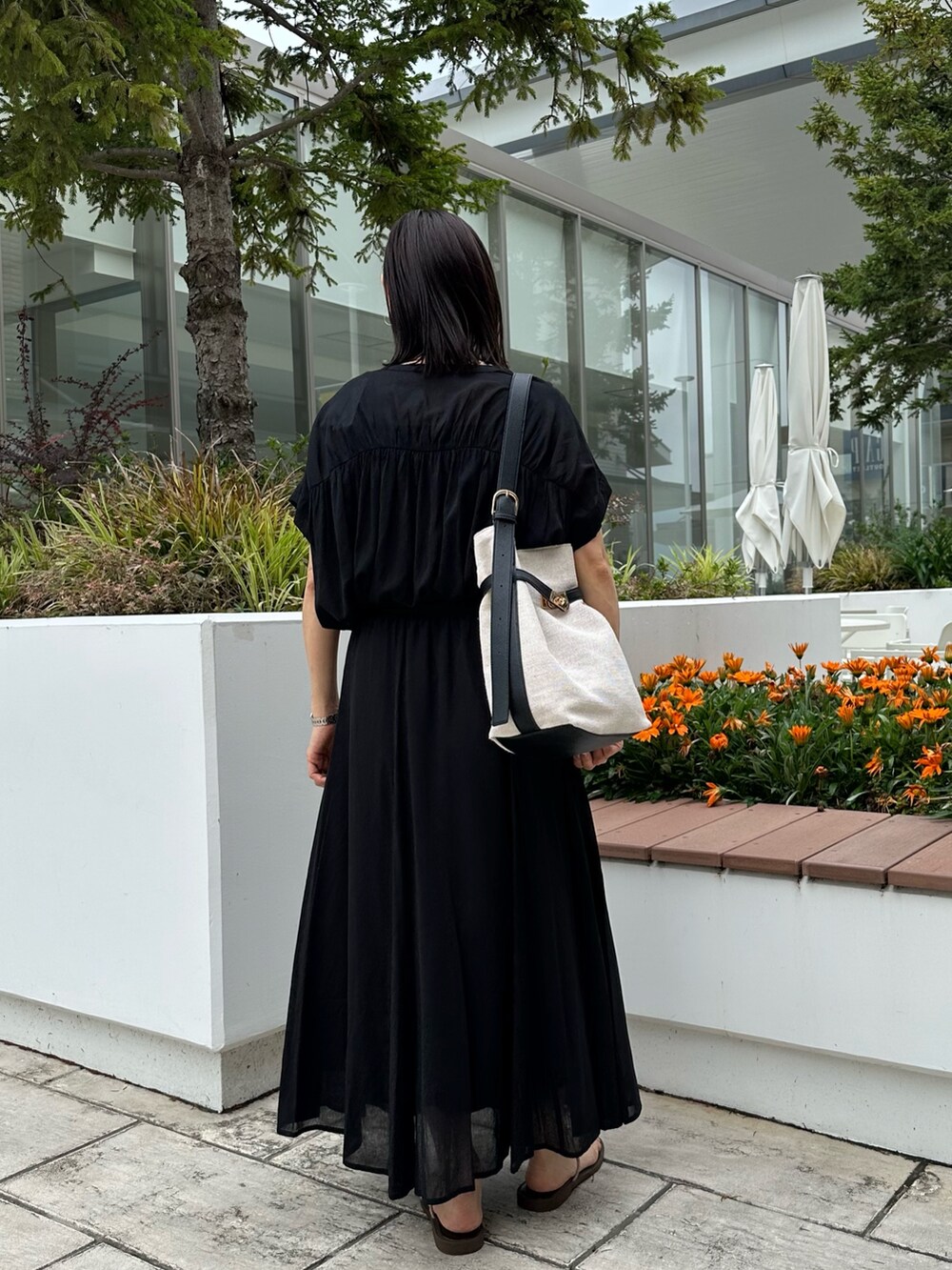 ブラック系のシャツ/ブラウス、ブラック系のスカート、ゴールド系のネックレスを着用したレディースの夏コーディネートの4枚目の写真