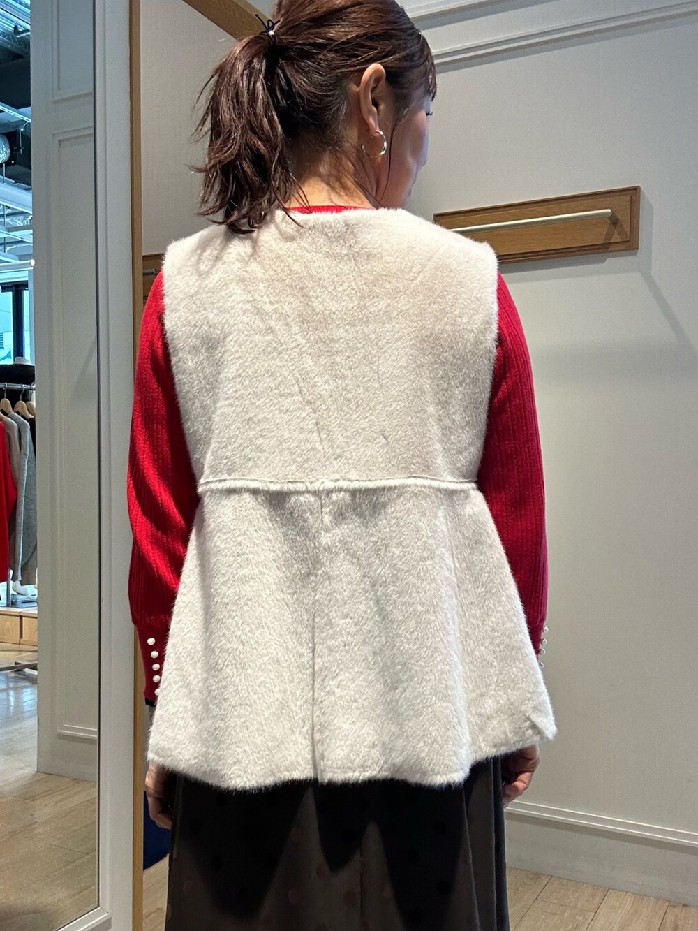 レッド系のニット/セーター、ブラウン系のスカート、ブラック系のトートバッグを着用したレディースの秋コーディネートの5枚目の写真