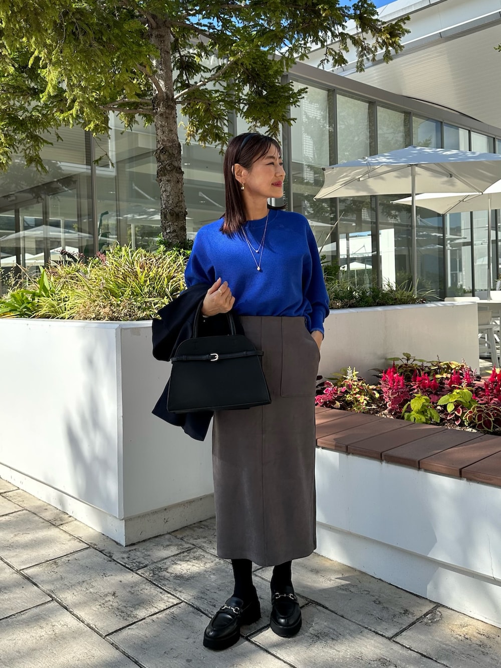 ブルー系のテーラードジャケット、ブルー系のニット/セーター、グレー系のスカートを着用したレディースの秋コーディネートの6枚目の写真