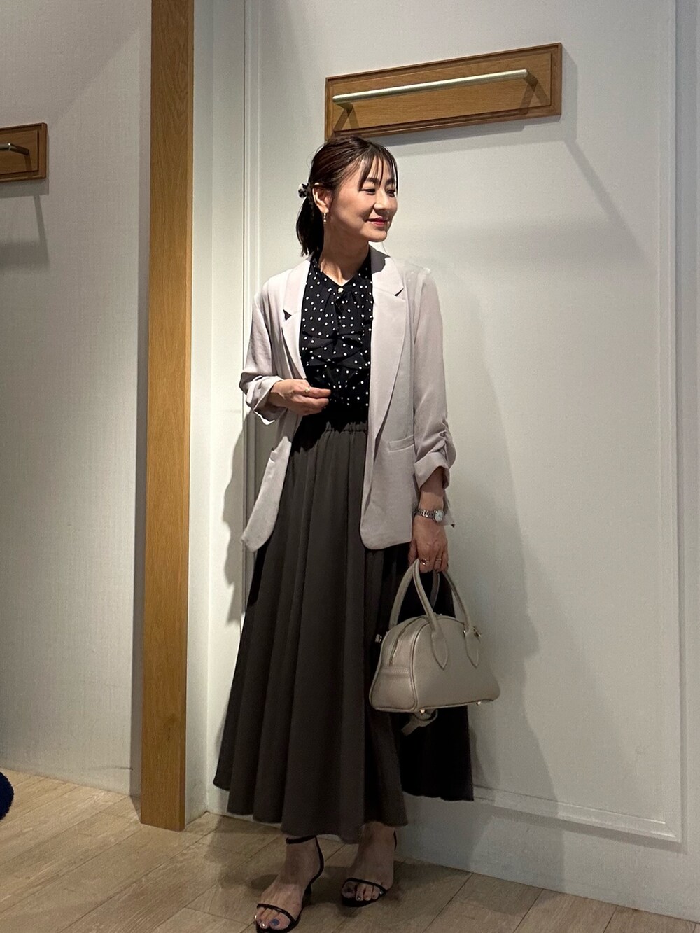 ベージュ系のテーラードジャケット、ベージュ系のボストンバッグ、ブラック系のサンダルを着用したレディースの夏コーディネートの2枚目の写真
