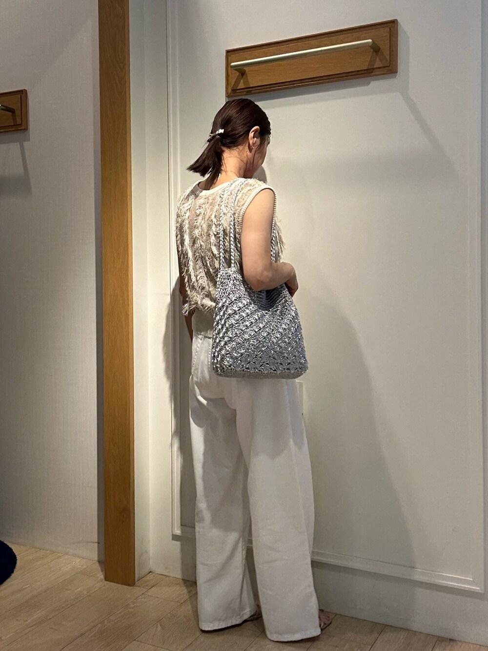 ベージュ系のニット/セーター、ホワイト系のデニムパンツ、ゴールド系のヘアゴムを着用したレディースの夏コーディネートの4枚目の写真