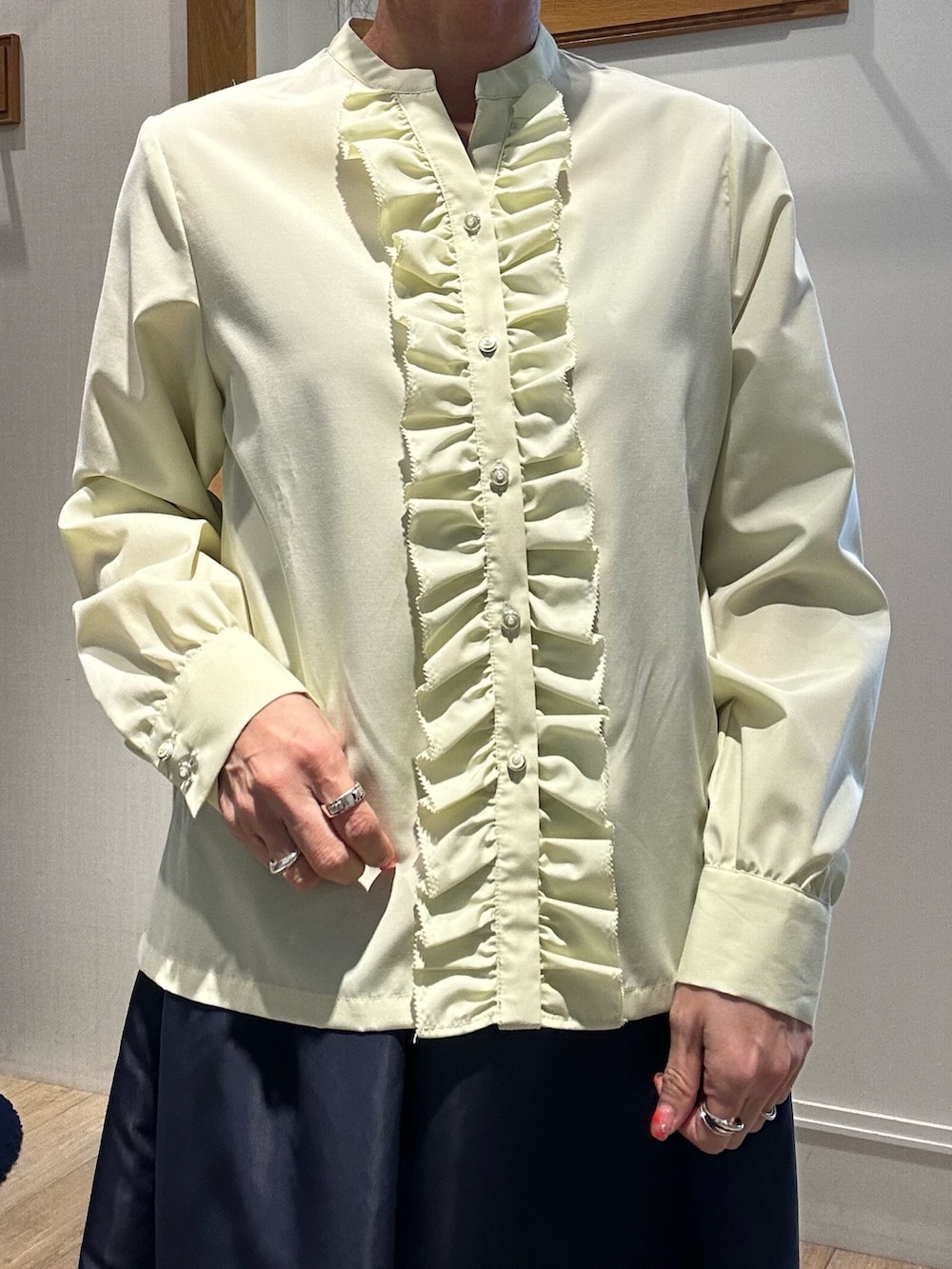 イエロー系のシャツ/ブラウス、ブルー系のスカート、ホワイト系のニット/セーターを着用したレディースの冬コーディネートの3枚目の写真