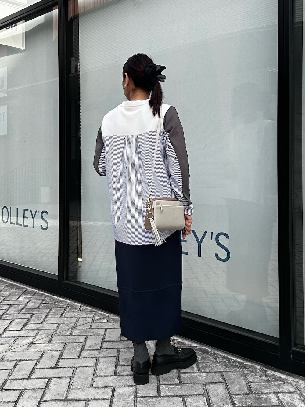 ブルー系のスカート、ホワイト系のニット/セーター、ホワイト系のショルダーバッグを着用したレディースの冬コーディネートの3枚目の写真