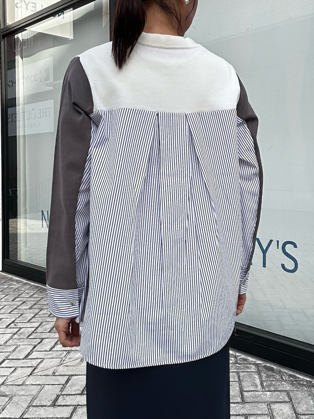 ブルー系のスカート、ホワイト系のニット/セーター、ホワイト系のショルダーバッグを着用したレディースの冬コーディネートの8枚目の写真