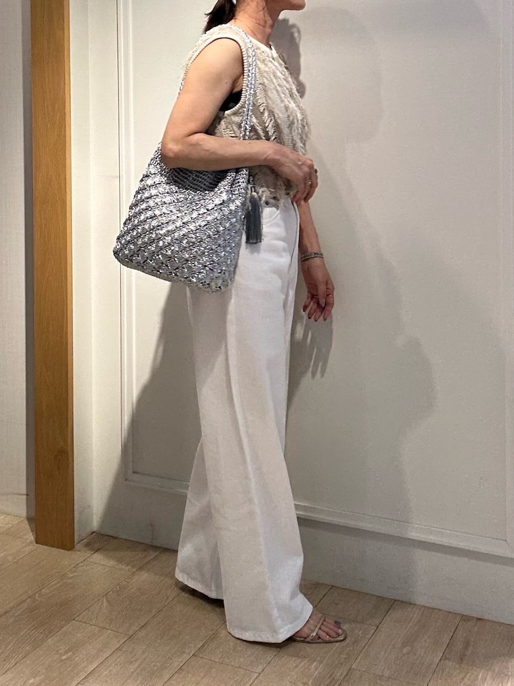 ベージュ系のニット/セーター、ホワイト系のデニムパンツ、ゴールド系のヘアゴムを着用したレディースの夏コーディネートの7枚目の写真