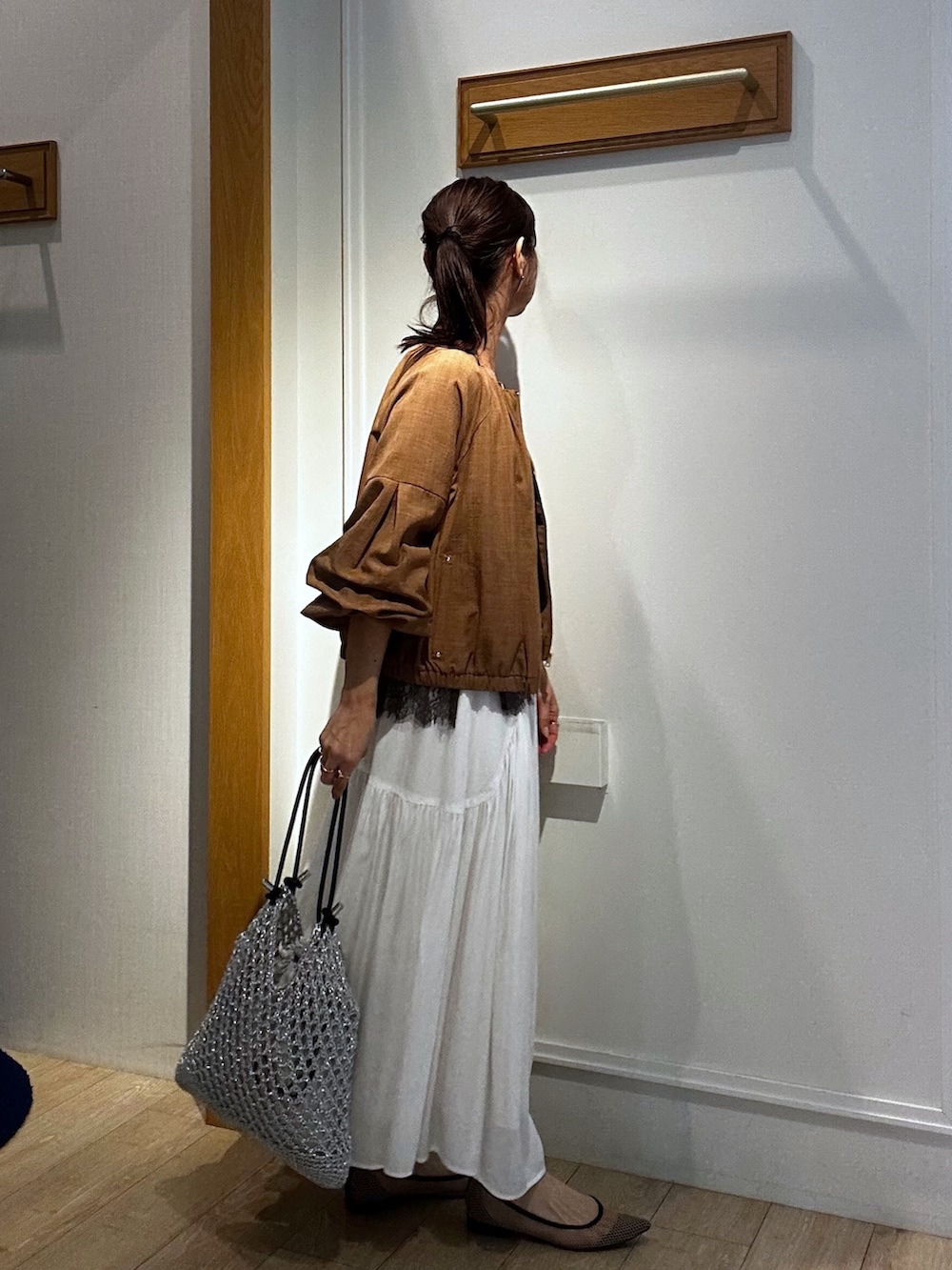 イエロー系のブルゾン、ブラウン系のTシャツ/カットソー、ホワイト系のスカートを着用したレディースの春コーディネートの2枚目の写真