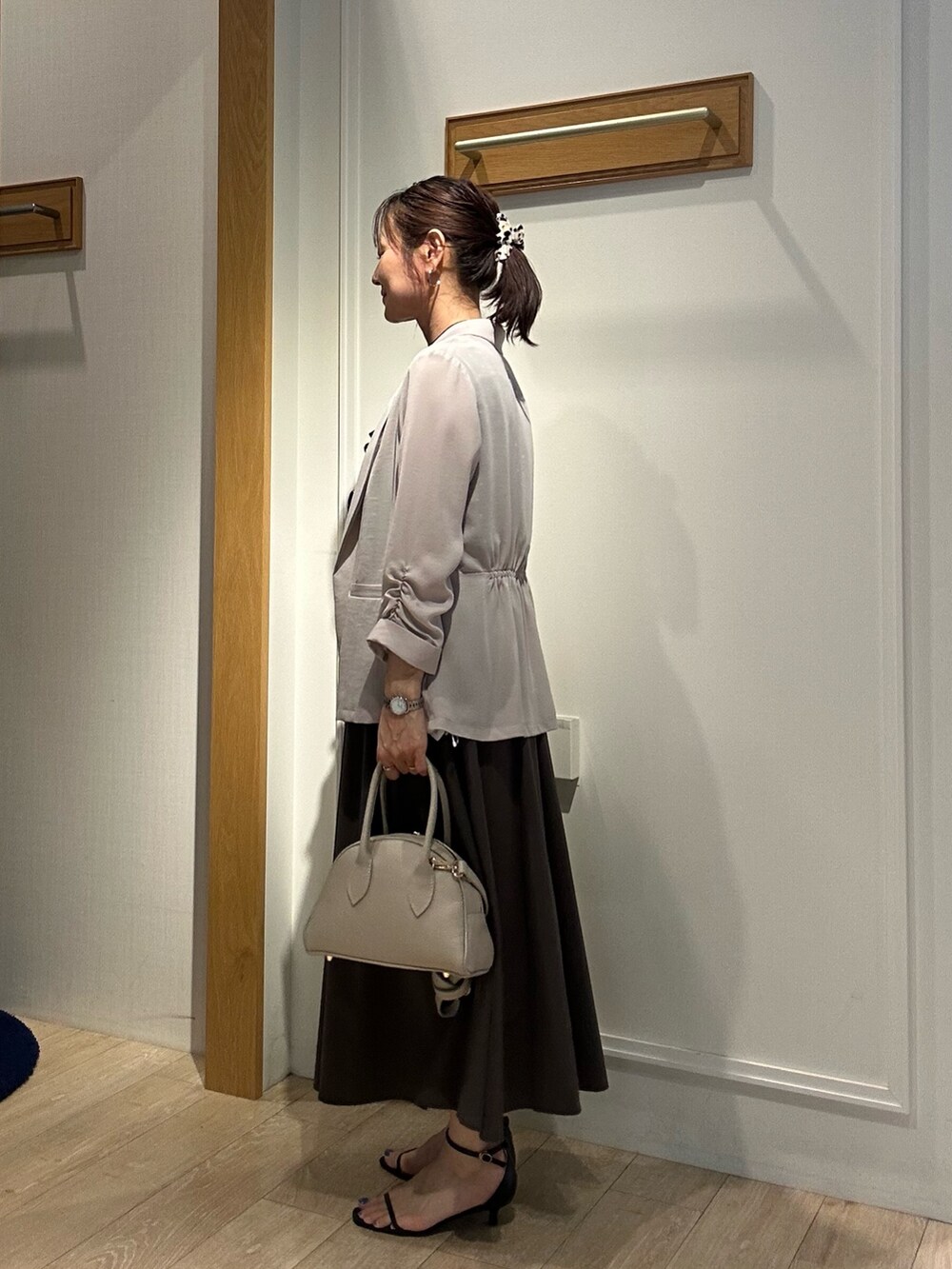 ベージュ系のテーラードジャケット、ベージュ系のボストンバッグ、ブラック系のサンダルを着用したレディースの夏コーディネートの4枚目の写真