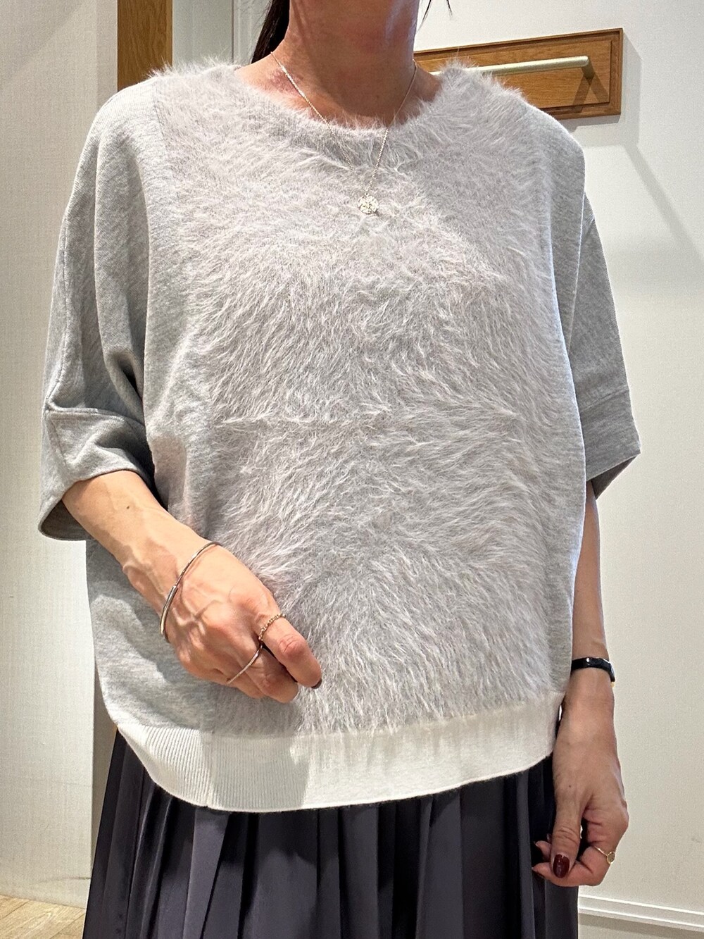 ブラック系のショルダーバッグ、グレー系のニット/セーター、ホワイト系のスカートを着用したレディースの秋コーディネートの4枚目の写真