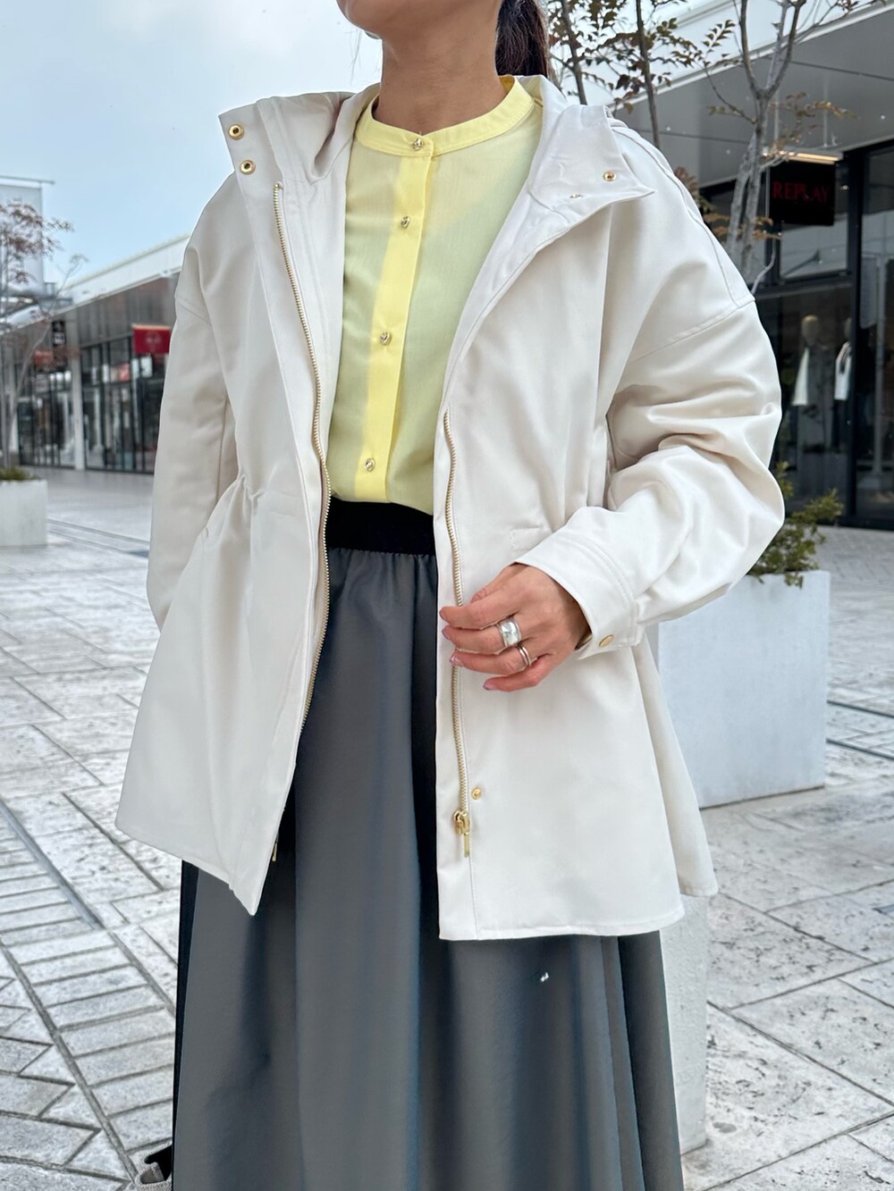 ホワイト系のブルゾン、イエロー系のシャツ/ブラウス、グリーン系のスカートを着用したレディースの冬コーディネートの6枚目の写真