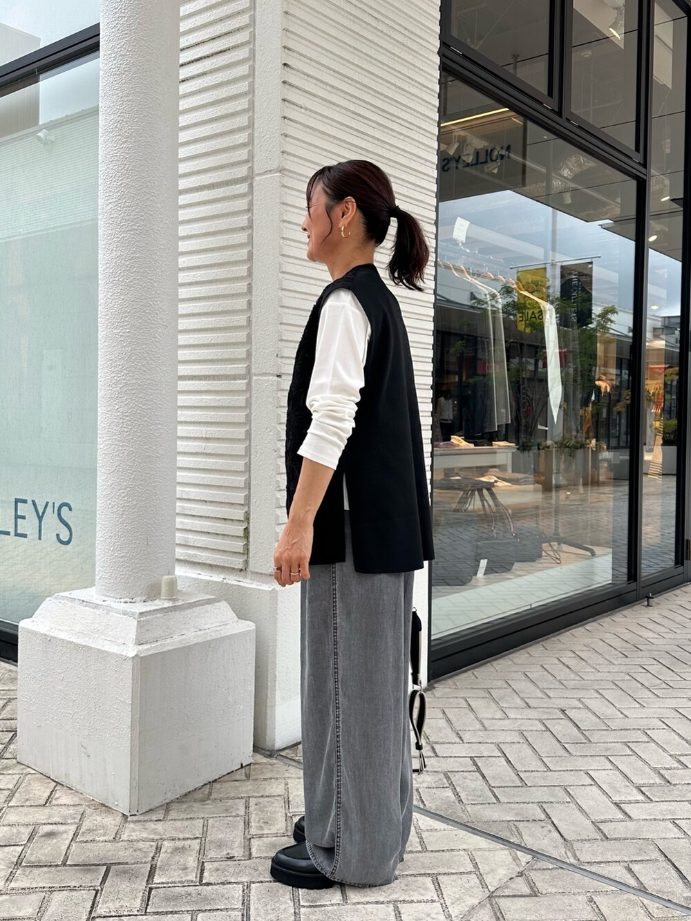 グレー系のデニムパンツ、ブラック系のニット/セーター、グレー系のトートバッグを着用したレディースの秋コーディネートの2枚目の写真