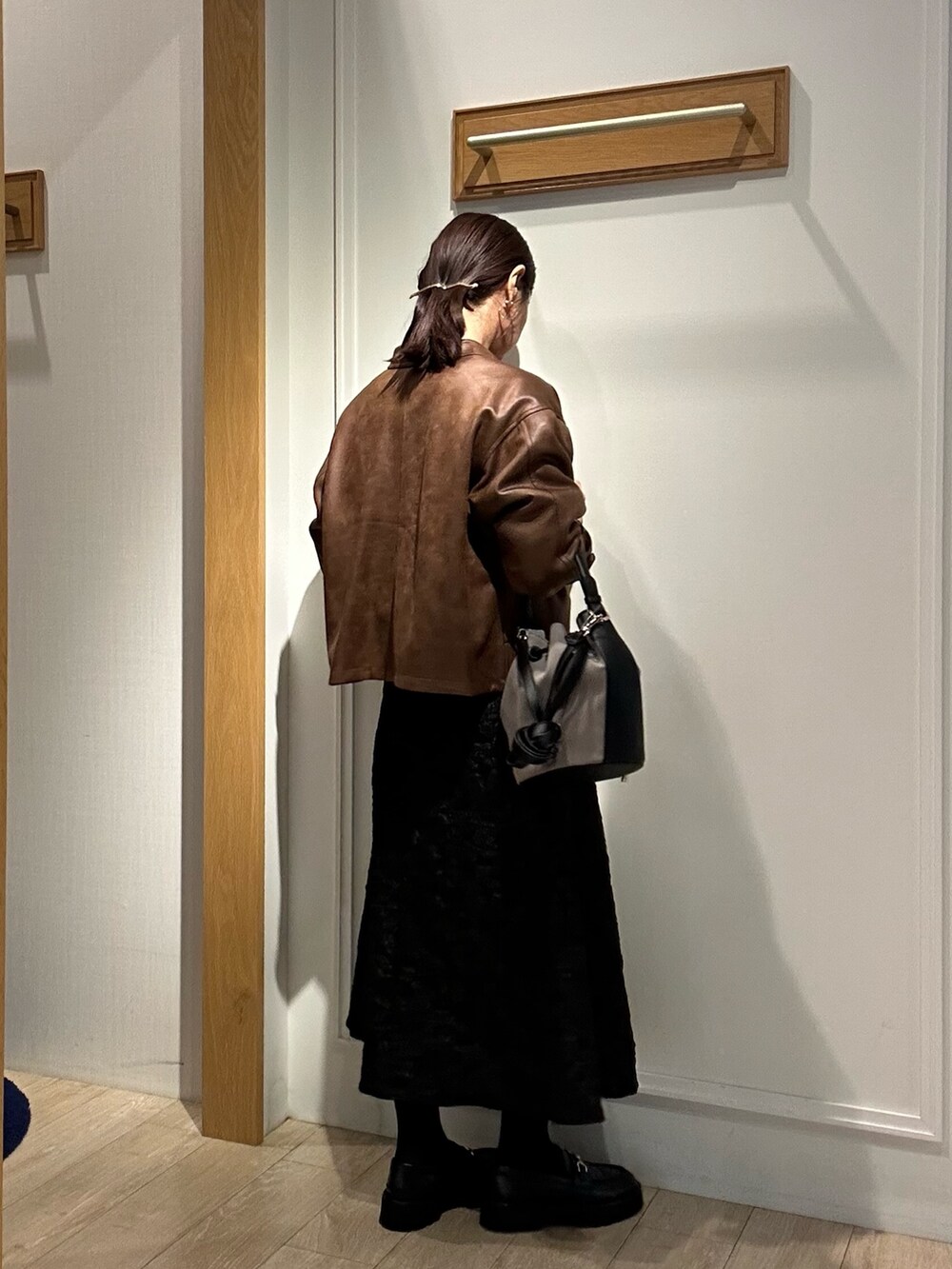 イエロー系のブルゾン、グリーン系のニット/セーター、グレー系のスカートを着用したレディースの秋コーディネートの3枚目の写真