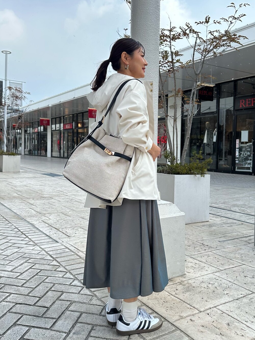 ホワイト系のブルゾン、イエロー系のシャツ/ブラウス、グリーン系のスカートを着用したレディースの冬コーディネートの2枚目の写真