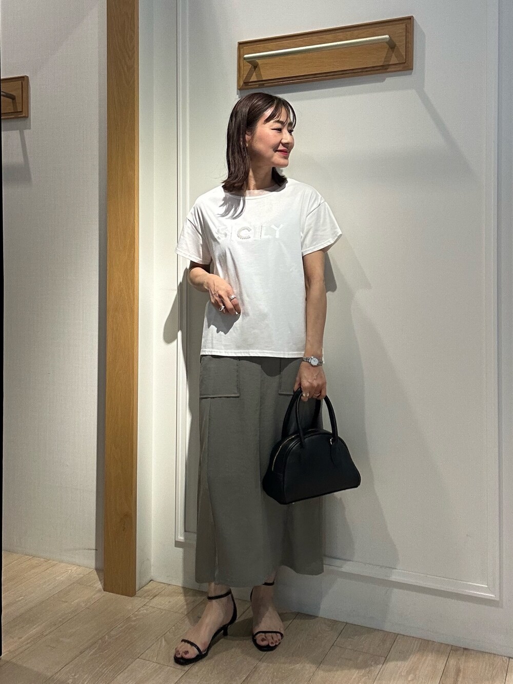 グリーン系のスカート、ホワイト系のTシャツ/カットソー、ブラック系のボストンバッグを着用したレディースの夏コーディネートの3枚目の写真