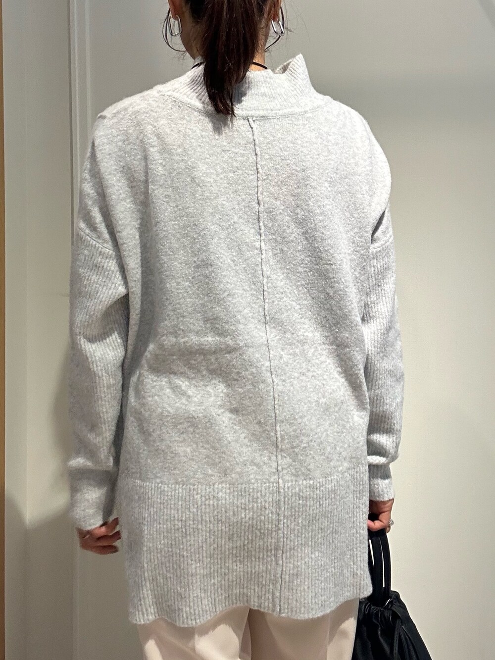 グレー系のニット/セーター、ホワイト系のその他パンツ、ブラック系のショルダーバッグを着用したレディースの冬コーディネートの6枚目の写真