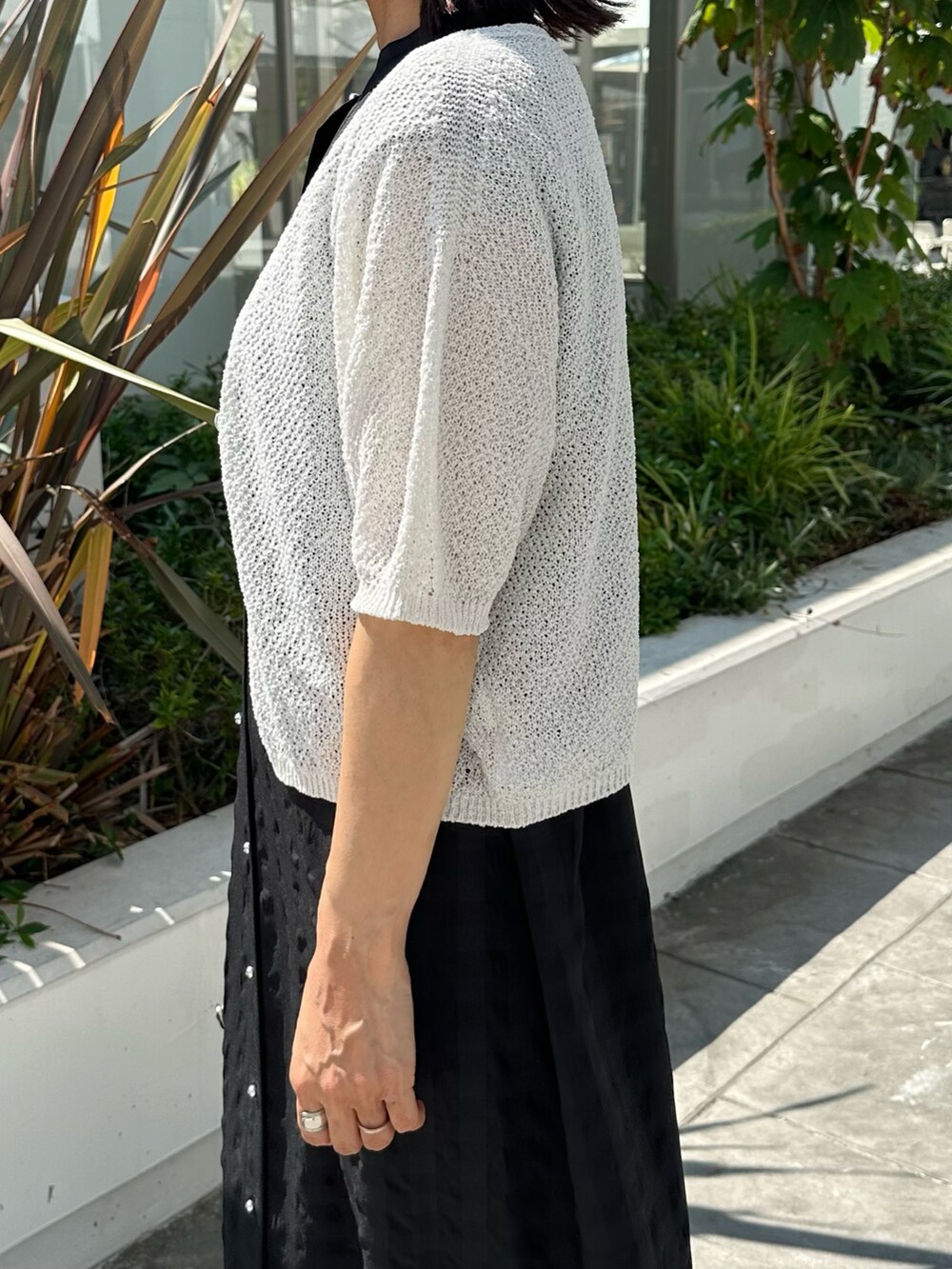 ブラック系のワンピース、ホワイト系のカーディガン/ボレロ、ブラック系のバックパック/リュックを着用したレディースの夏コーディネートの5枚目の写真