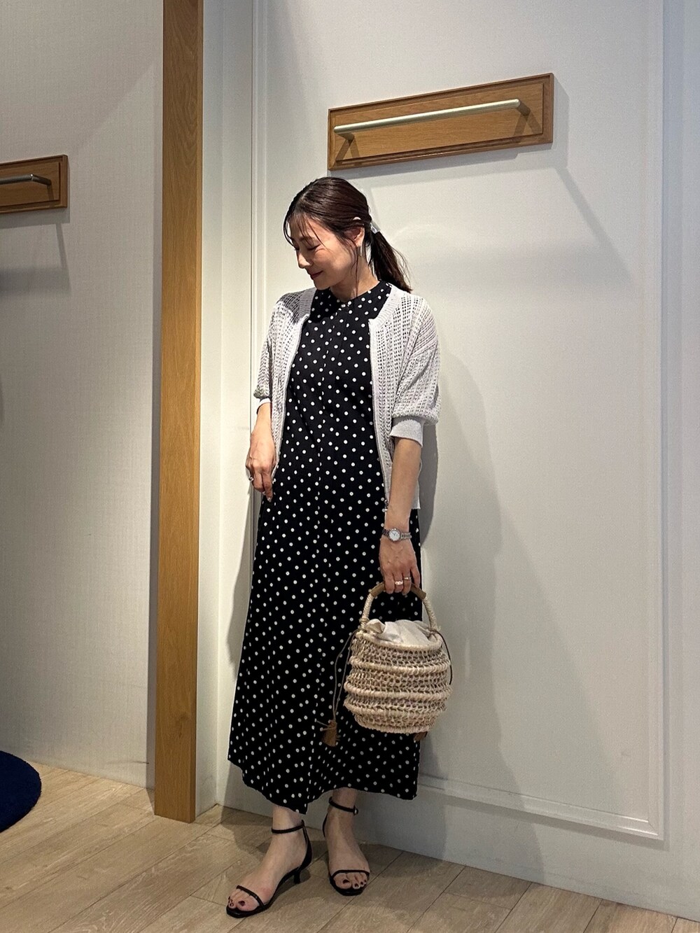 グレー系のニット/セーター、ブラック系のワンピース、ブラック系のサンダルを着用したレディースの春コーディネートの2枚目の写真