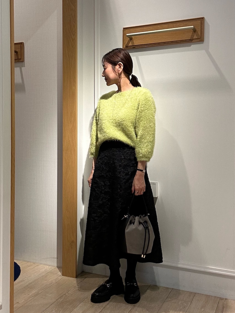 イエロー系のブルゾン、グリーン系のニット/セーター、グレー系のスカートを着用したレディースの秋コーディネートの10枚目の写真