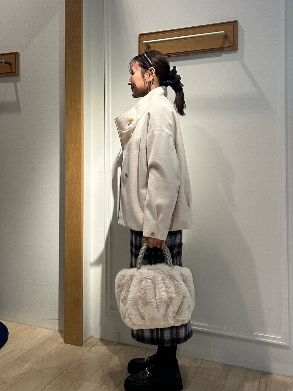 ホワイト系のトートバッグ、ホワイト系のテーラードジャケット、ブラック系のニット/セーターを着用したレディースの冬コーディネートの2枚目の写真