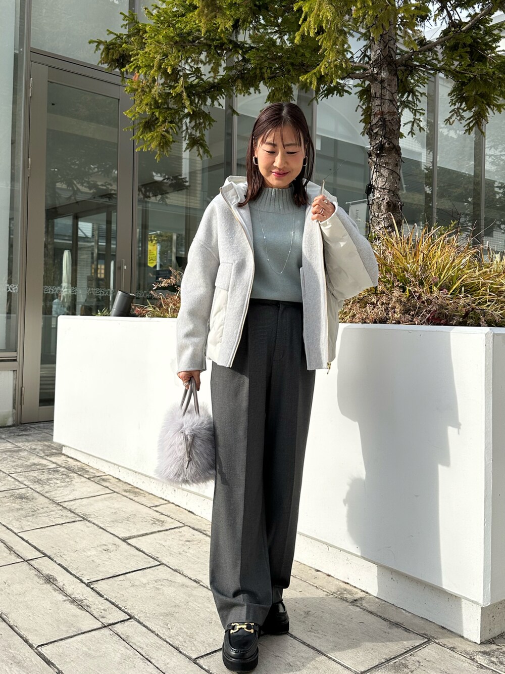 グレー系のその他アウター、オレンジ系のニット/セーターを着用したレディースの冬コーディネートの2枚目の写真