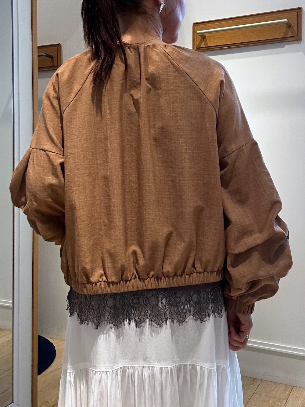 イエロー系のブルゾン、ブラウン系のTシャツ/カットソー、ホワイト系のスカートを着用したレディースの春コーディネートの6枚目の写真