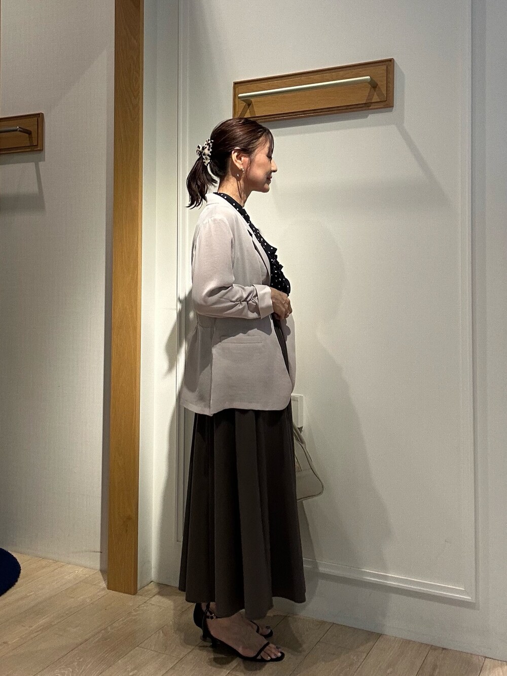 ベージュ系のテーラードジャケット、ベージュ系のボストンバッグ、ブラック系のサンダルを着用したレディースの夏コーディネートの3枚目の写真