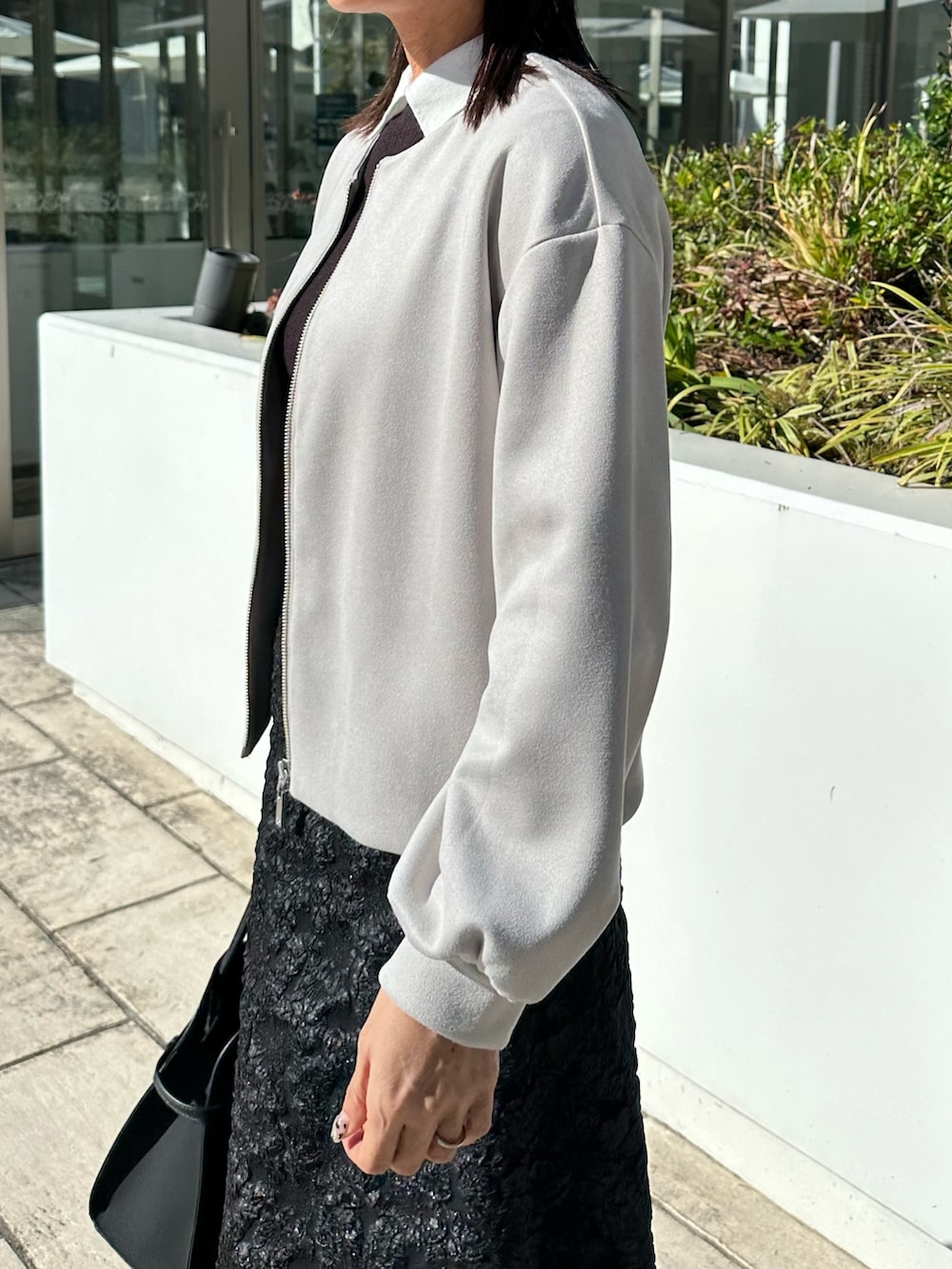 グレー系のブルゾン、ブラック系のニット/セーター、グレー系のスカートを着用したレディースの秋コーディネートの7枚目の写真