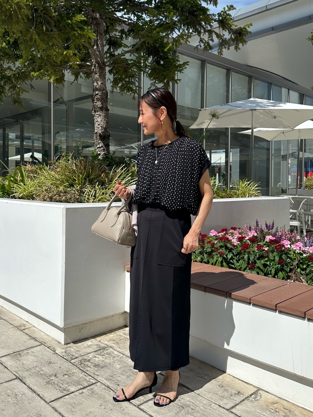 ブラック系のシャツ/ブラウス、ブラック系のスカート、ベージュ系のボストンバッグを着用したレディースの夏コーディネートの2枚目の写真