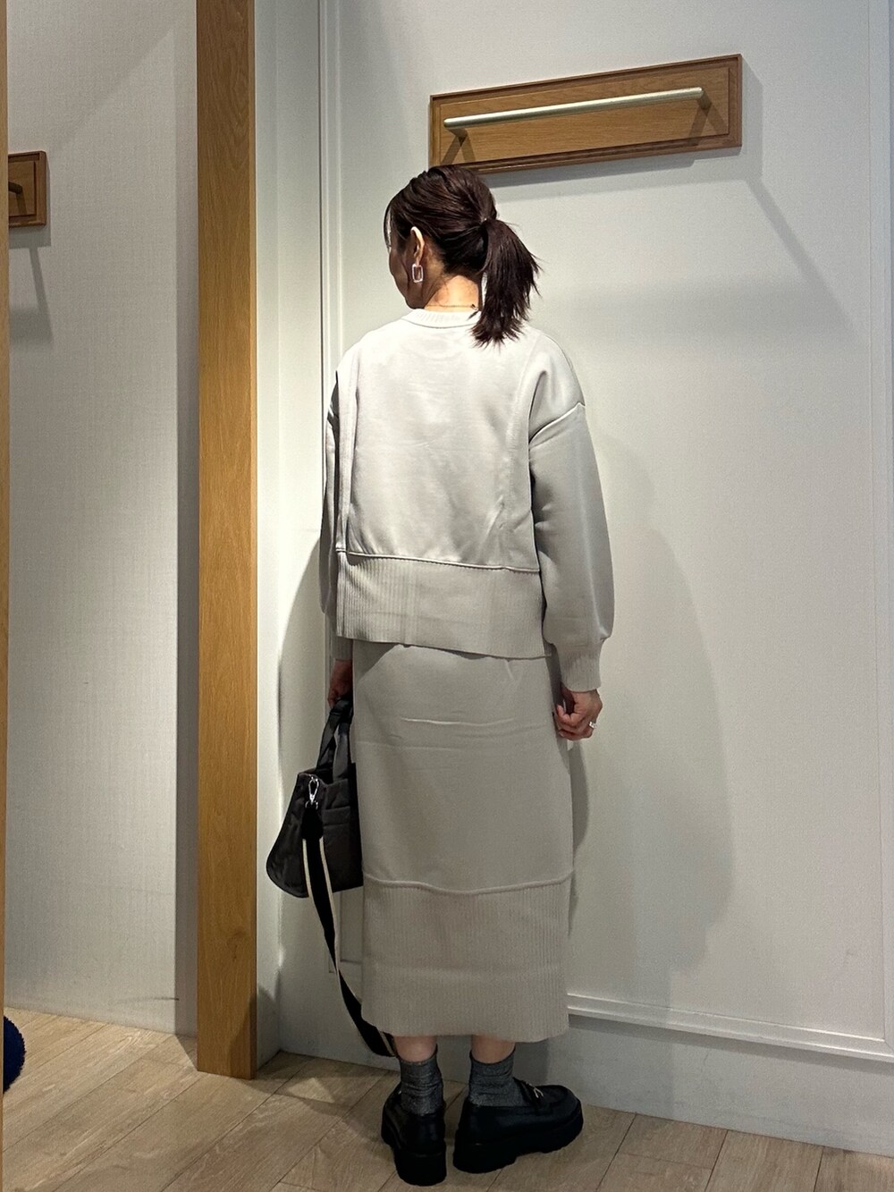 グレー系のトートバッグ、ベージュ系のスカート、ベージュ系のTシャツ/カットソーを着用したレディースの秋コーディネートの4枚目の写真