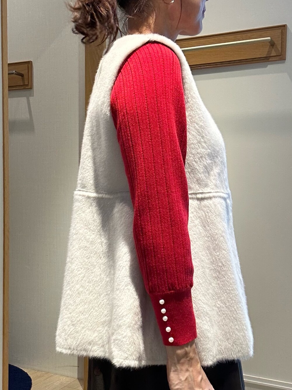 レッド系のニット/セーター、ブラウン系のスカート、ブラック系のトートバッグを着用したレディースの秋コーディネートの4枚目の写真