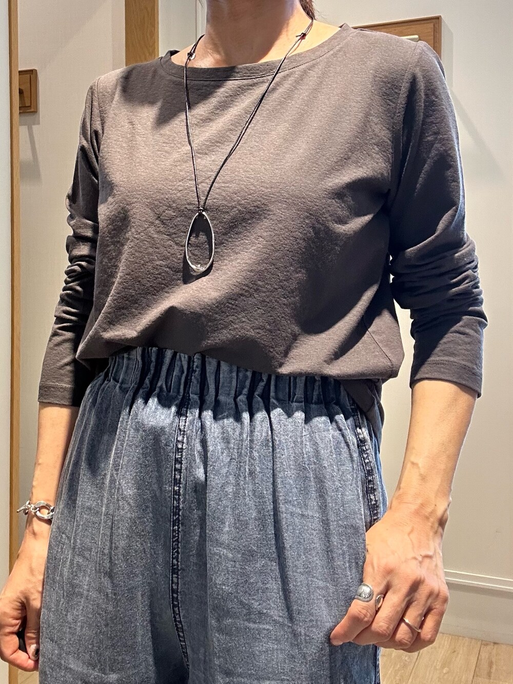 グレー系のTシャツ/カットソー、ブルー系のデニムパンツ、ブラウン系のブルゾンを着用したレディースの秋コーディネートの7枚目の写真